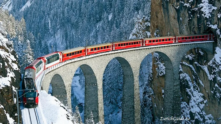 A red train crossing the Landwasser viaduct in snow